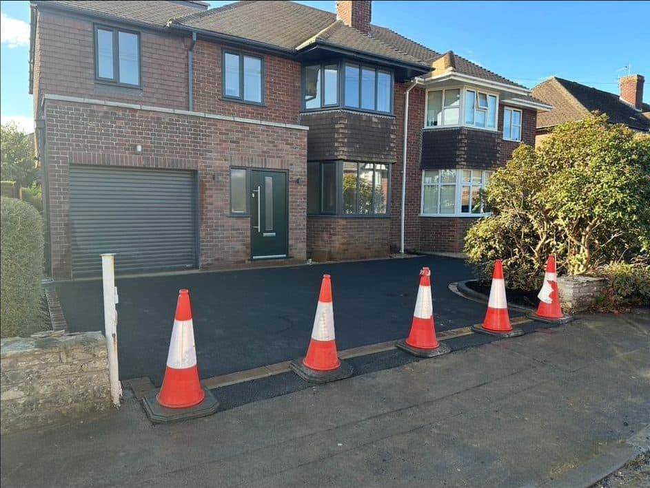 New black tarmac driveway completed across the front of a double-fronted brick house