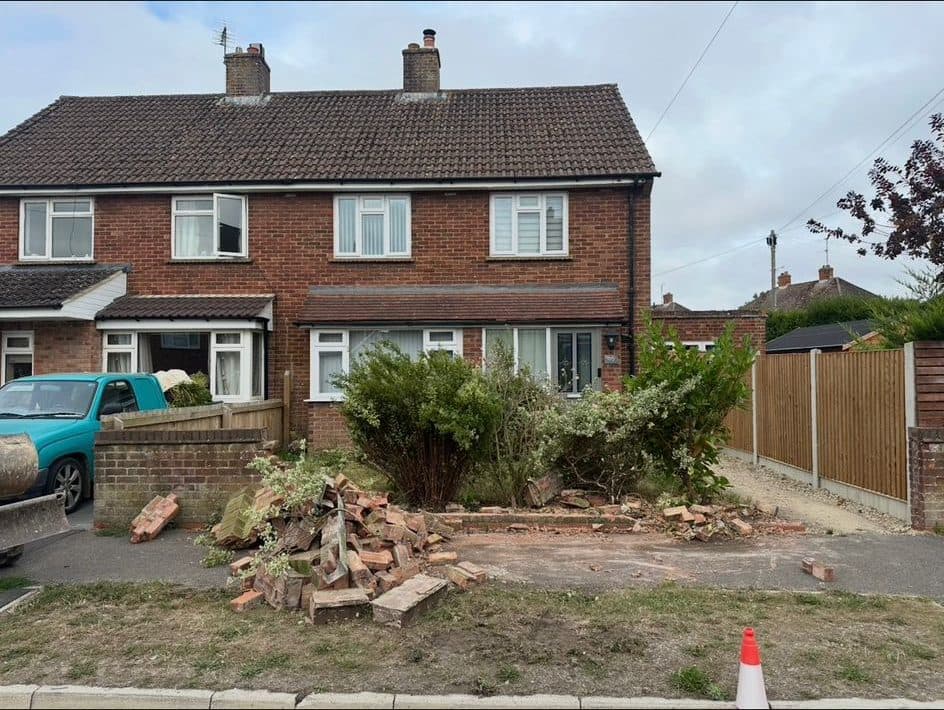 Overgrown front garden with a demolished brick wall before landscaping work