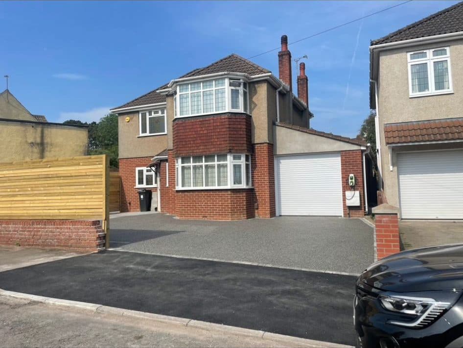 Completed grey resin-bound driveway in the sun at a rendered 1930s detached house
